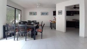 Un comedor amplio con una mesa grande y sillas, un ventilador de techo y cuadros en las paredes.