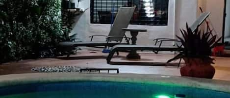 Una piscina al aire libre, sillones reclinables de piscina