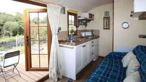 Eine kompakte Küche mit Spüle, Mikrowelle und Schränken, ein Essbereich mit Tisch und Stühlen sowie eine Sitzecke mit Sofa.