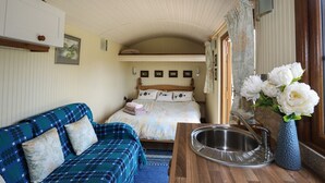 Ein gemütliches Schlafzimmer mit einem Bett, einem blauen Sofa, einem Holztisch mit Waschbecken und einer Vase mit Blumen.