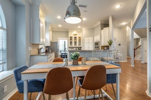 A modern kitchen with a dining area, wooden flooring, and a large pendant light. - Family Escape ✓PETS OK Game Room Fenced Backyard (Plano)