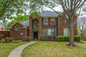 Stunning two-story home with a central entrance and beautifully manicured lawn.