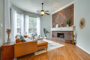 Cozy living room with a comfortable sofa set, fireplace, and ceiling fan.