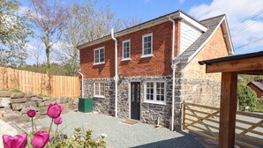 A two-story house with a stone facade and a brick upper level, featuring a front door and two windows. - Tan Y Capel (Llanbrynmair)