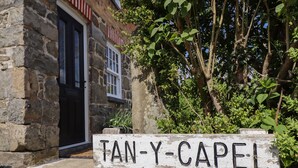 A rustic stone building with a wooden sign reading "TAN-Y-CAPEL". - Tan Y Capel (Llanbrynmair)