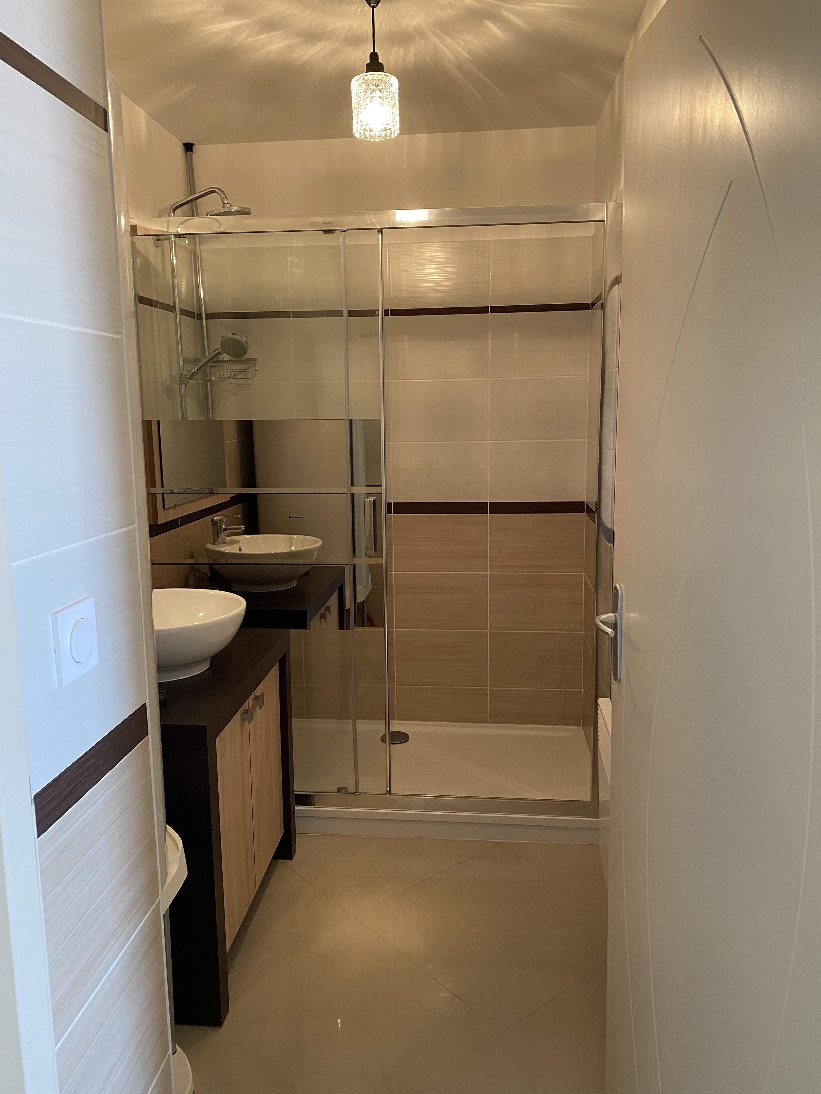 A modern bathroom with a glass-enclosed shower, a sink, and a mirror.
