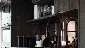 A modern kitchen with dark wood cabinetry, a stainless steel sink, and a built-in oven.