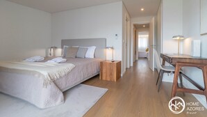 Moderni hotellihuone, jossa on suuri sänky, yöpöydät, työpöytä ja tuoli.