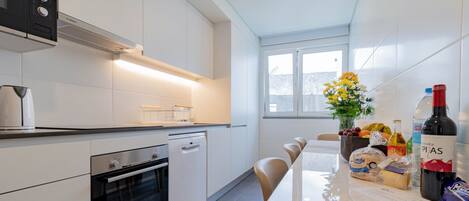 A modern kitchen with white cabinets, a Bosch oven, and a dining area with a table set for four.