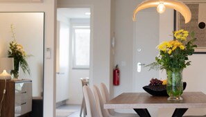Un espace repas moderne avec une table en bois, des chaises blanches et un vase rempli de fleurs jaunes.