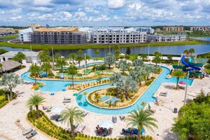 A resort with a large swimming pool, palm trees, and a water slide.