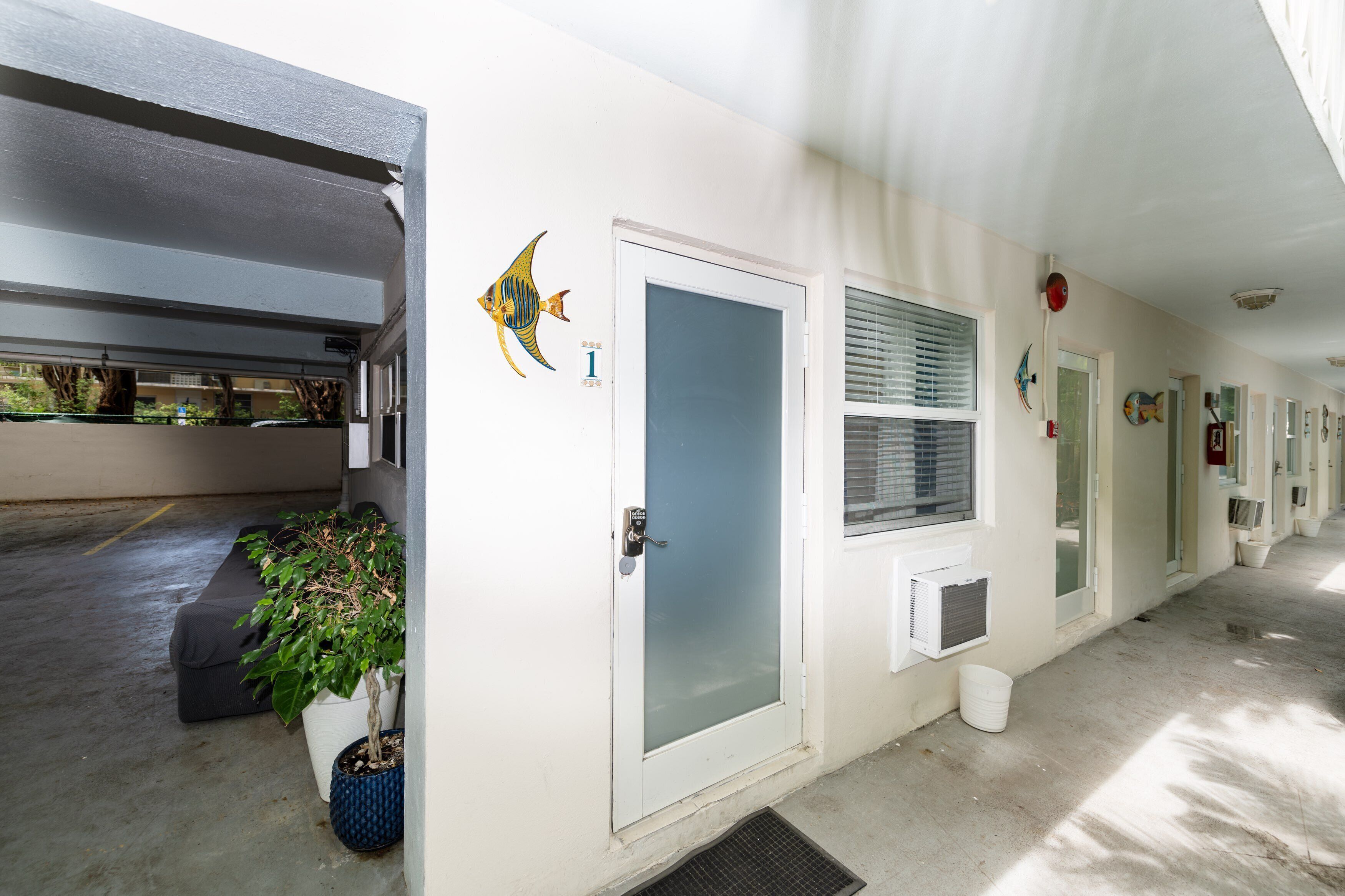 A hallway with doors numbered 1 and 2, a potted plant, and a fish decal on the wall.
