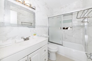 Une salle de bain moderne avec un lavabo en marbre, une douche à parois de verre et des toilettes blanches.