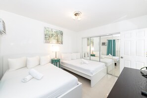 Une chambre d’hôtel avec deux lits, un bureau, un miroir et un tableau au mur.