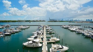 Un port de plaisance où de nombreux bateaux sont amarrés à un quai, avec une vue sur les gratte-ciel de la ville en arrière-plan et un ciel dégagé.