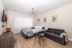 A modern bedroom with a bed, a sofa, a desk, and a TV. - OCEAN DRIVE APARTMENTS (Miami Beach)