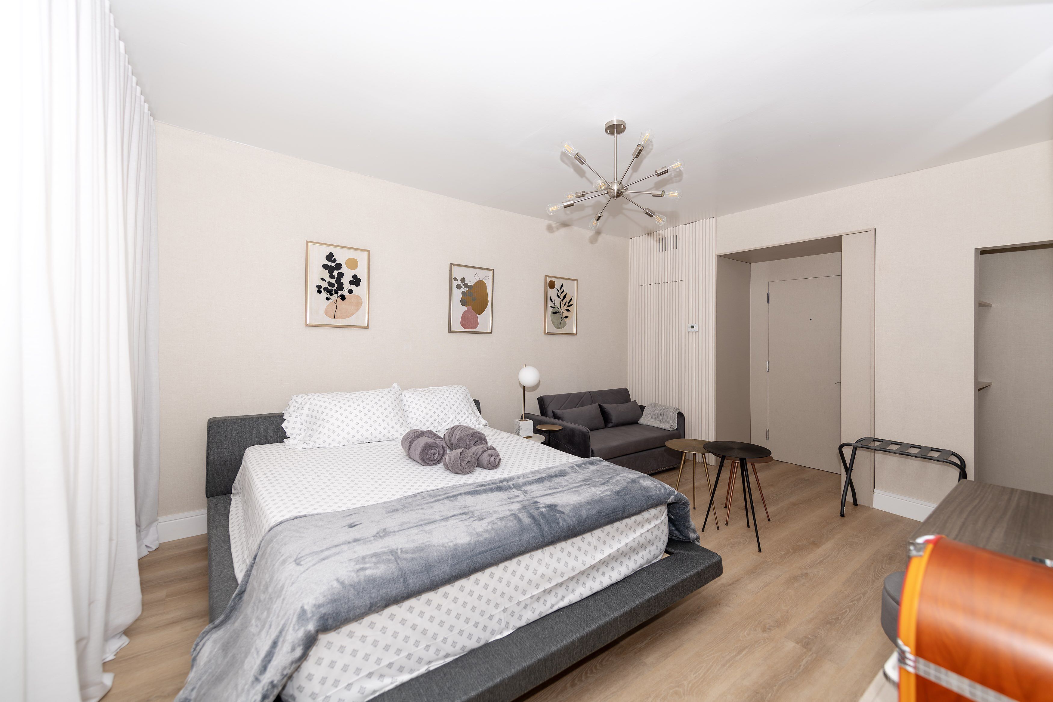 Quarto moderno com cama, sofá, mesinha e cadeira.