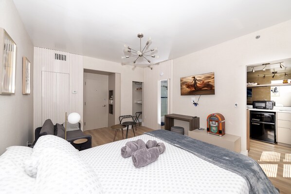 Une chambre d’hôtel moderne équipée d’un lit, d’un bureau, d’une chaise, d’un four à micro-ondes et d’une petite kitchenette.