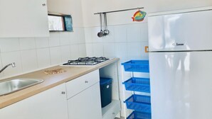 A kitchen with white cabinets, a gas stove, a sink, and a white refrigerator. - Blue Med Smurf, Palinuro, Cilento (Palinuro)