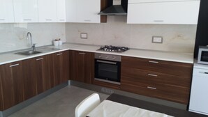 Een moderne keuken met witte kasten, een roestvrijstalen spoelbak, een gasfornuis en een inbouwoven.