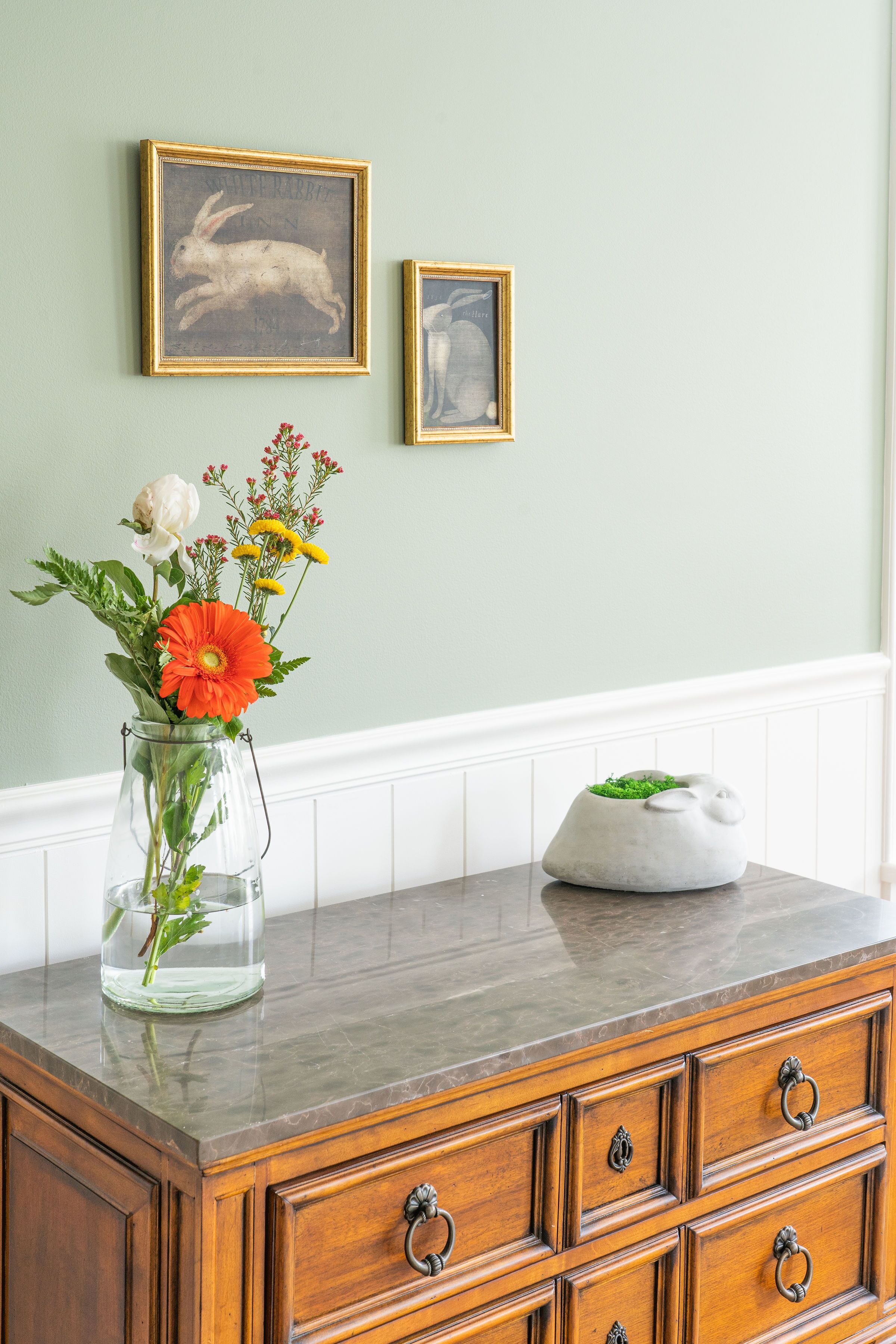 A wooden dresser with drawers and a vase of flowers on top.