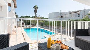 Un balcón con piscina, mobiliario exterior y productos para el desayuno.
