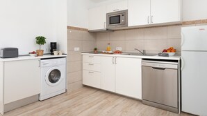 Una cocina moderna con armarios blancos, microondas, tostadora, lavadora y lavavajillas.