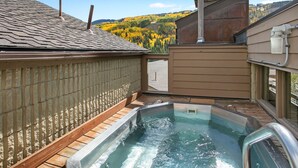 A rooftop hot tub with a view of autumn foliage and a wooden deck. - Lionshead Village Condo, Perfect Location 100 Yards from Slopes, Hot Tub! (Vail)