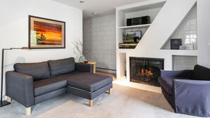 A modern living room with a sectional sofa, a fireplace, and a TV on a shelf. - Lionshead Village Condo, Perfect Location 100 Yards from Slopes, Hot Tub! (Vail)
