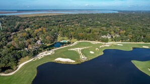 An aerial view of a golf course with a large lake, surrounded by dense forest and residential areas. - RARE Direct Oceanfront Condo with TWO private balconies within OMNI resort (Fernandina Beach)
