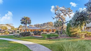 A residential property with a well-maintained lawn, a paved driveway, and a large house with a front porch. - RARE Direct Oceanfront Condo with TWO private balconies within OMNI resort (Fernandina Beach)