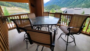 Un espace extérieur abrité, avec une table et des chaises, offrant une vue sur un paysage montagneux.
