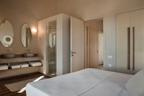 A bedroom with a large bed, a vanity with two sinks, a mirror, and a walk-in closet. - Zeus Exclusive Villas (Kefalonia)