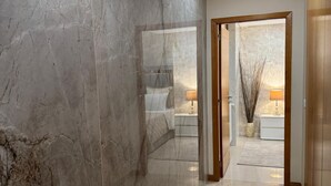 A hallway with marble walls and a tiled floor leading to a bedroom.