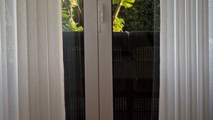 A sliding glass door with a view of a tropical landscape, including banana trees and a distant mountain range.