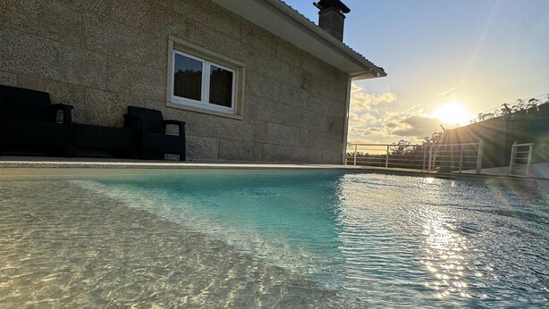 A swimming pool with clear water, a stone wall, and a window.