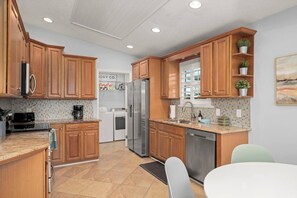 A modern kitchen with wooden cabinets, stainless steel appliances, and a tiled backsplash.