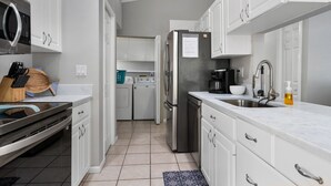 A modern kitchen with white cabinets, stainless steel appliances, and a built-in oven.
