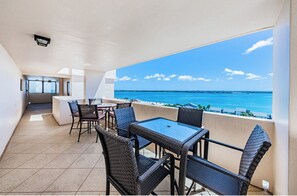 A balcony with a view of the ocean, wicker furniture, and a small bar area. - Beachfront condo on Sand Key with balconies facing both Beach & The Intracoastal (Clearwater)