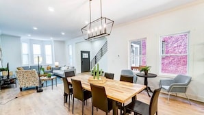 A spacious living area with a wooden dining table, black chairs, and a modern chandelier. - Modern Luxury Home: 7 Mins From Downtown-Sleeps 12 (Cincinnati)