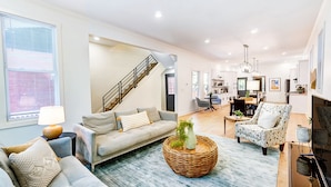 A modern living room with a sofa, a coffee table, and a dining area with chairs. - Modern Luxury Home: 7 Mins From Downtown-Sleeps 12 (Cincinnati)