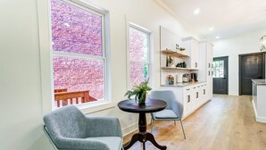 A modern kitchen with white cabinets, a dark countertop, and a brick wall visible through large windows. - Modern Luxury Home: 7 Mins From Downtown-Sleeps 12 (Cincinnati)