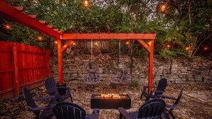 A patio with a fire pit, black chairs, and a red pergola with hanging lights. - Modern Luxury Home: 7 Mins From Downtown-Sleeps 12 (Cincinnati)