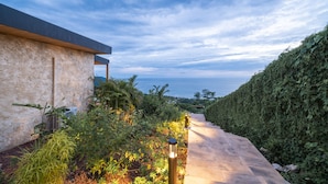 A pathway leading to a modern building with a view of the sea. - LALOON Luxury Suites - Adults Only (Cóbano)