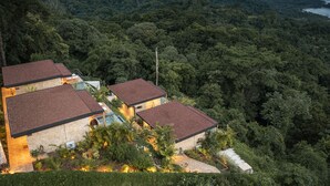 A hillside property with multiple buildings, lush greenery, and a view of the surrounding forest. - LALOON Luxury Suites - Adults Only (Cóbano)