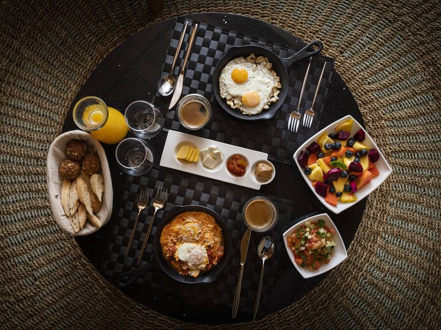 A breakfast setting with a variety of food items including eggs, toast, fruit, and beverages on a checkered table.
