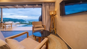 A modern living room with a large window, a sofa, a coffee table, and a lamp. - LALOON Luxury Suites - Adults Only (Cóbano)