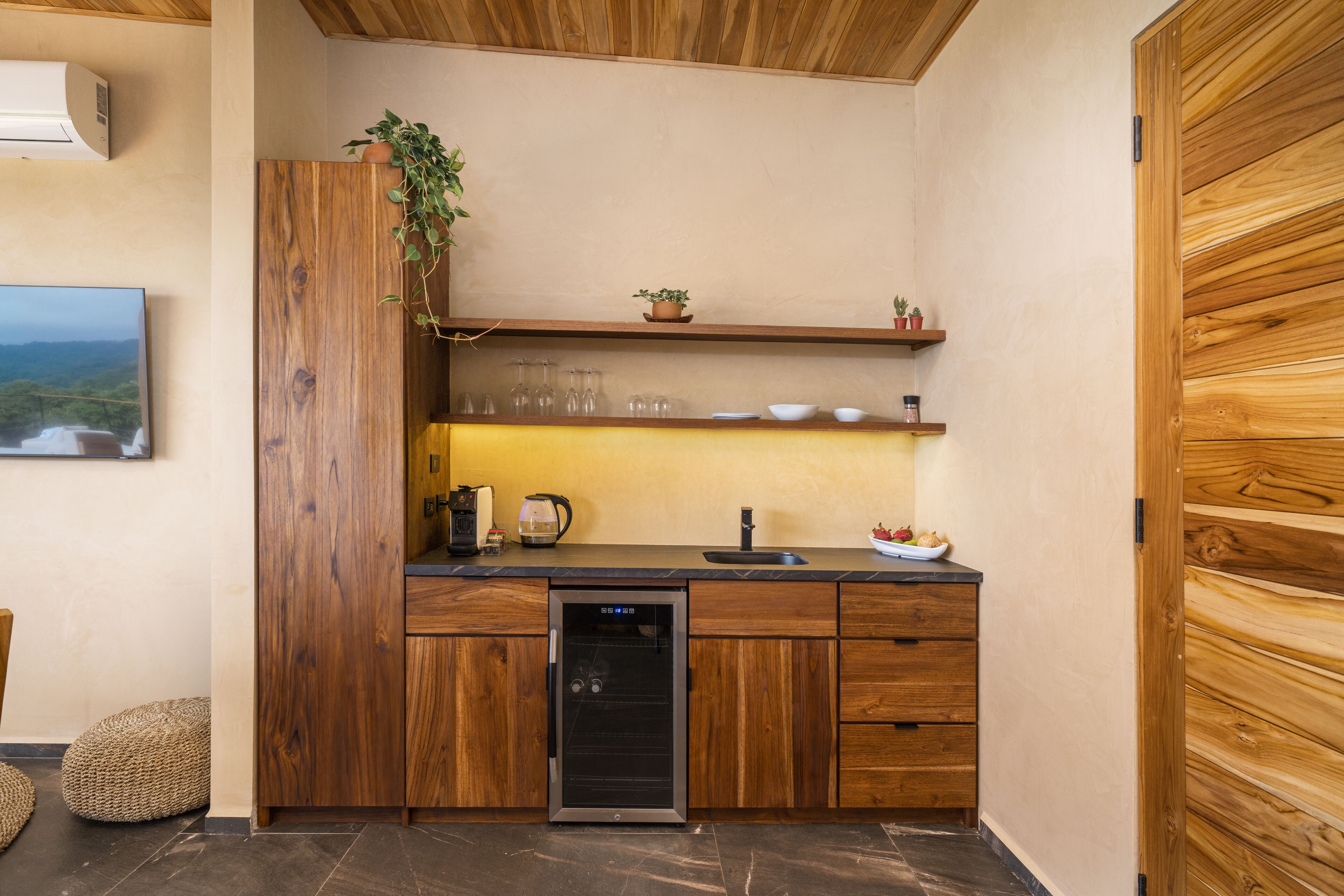 A compact kitchen with wooden cabinetry, a built-in dishwasher, and a small countertop with a sink and various kitchen items.