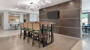 A modern dining area with a bar counter, cushioned chairs, and a contemporary light fixture. - Best Western Plus Grand Rapids MN (Grand Rapids)