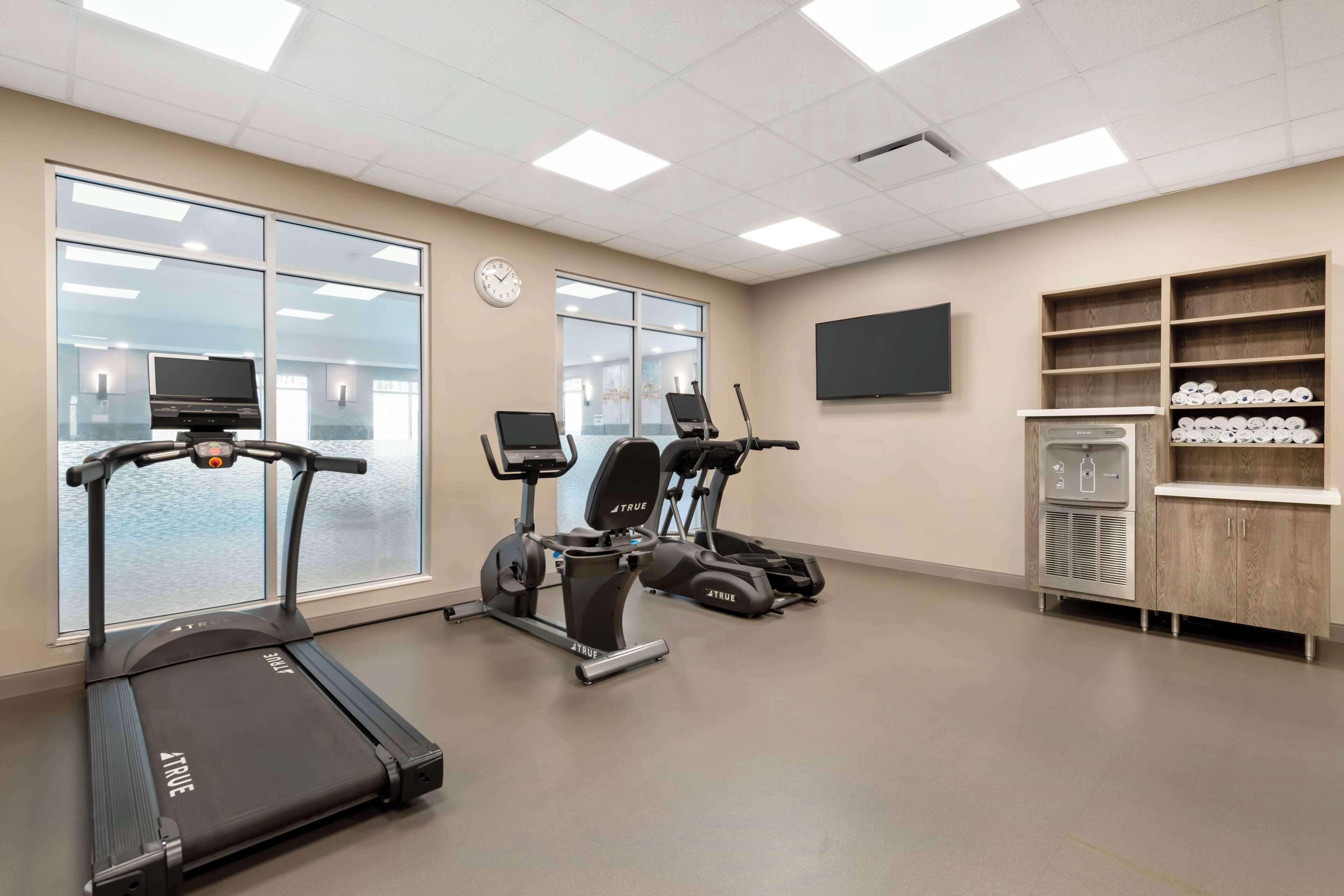 A fitness room with treadmills, a water dispenser, and a TV on the wall.